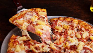 Hawaiian pizza with ham and pineapple cut into slices, cheese pull