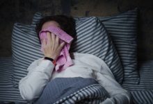 Mature woman is trying to sleep in bed but suffering from heat